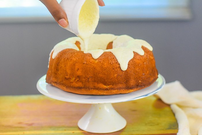 pouring vanilla frosting on pineapple pound cake