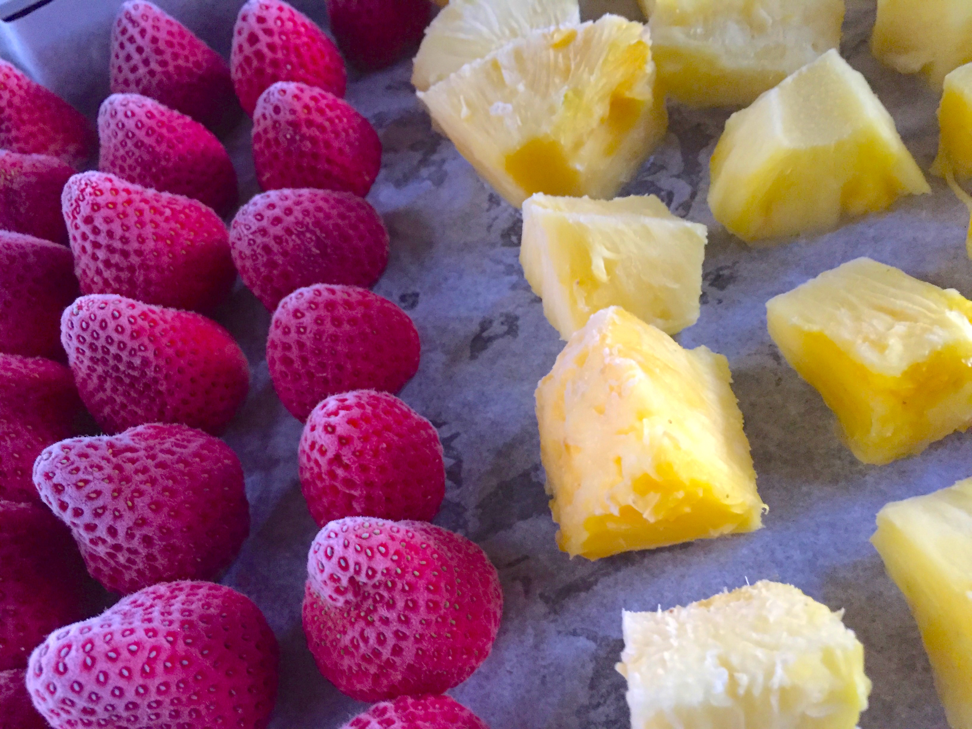 flash frozen pineapple chunks and strawberries on a baking sheet.