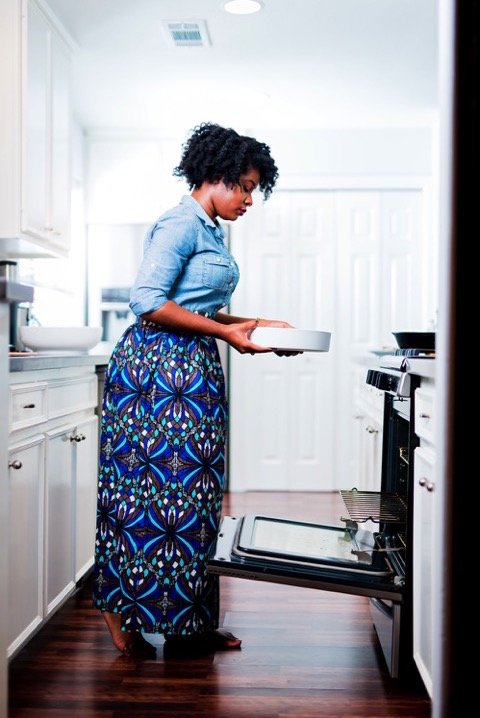 Jazzmine standing in kitchen holding dish to place into open oven