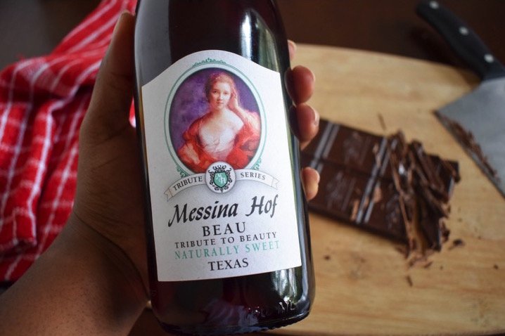 holding bottle of Messina Hof Beau wine