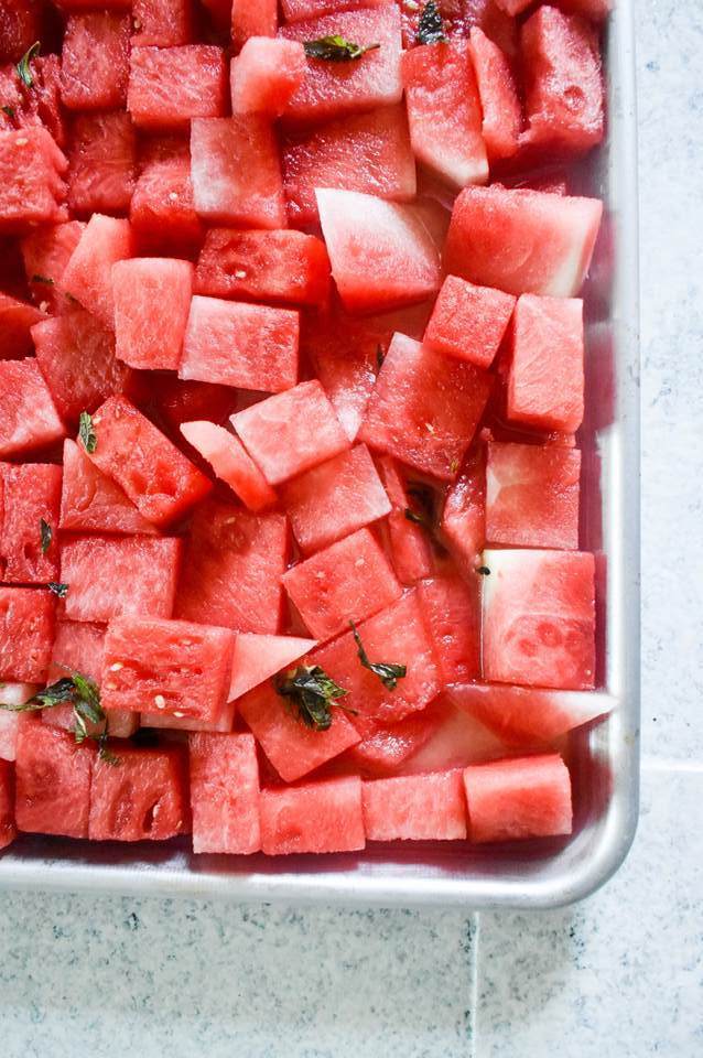 pieces of watermelon soaking in tequila on sheet pan.