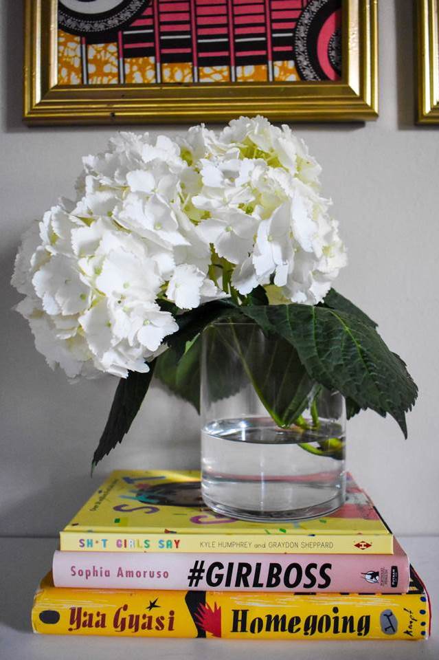 single white hydrangea in a clear vase on stack of three books