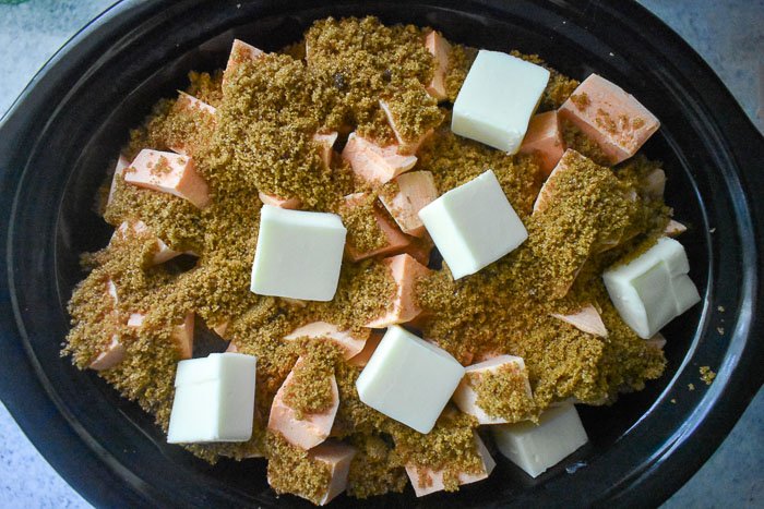 chunks of sweet potato, butter, and brown sugar mixture in slow cooker