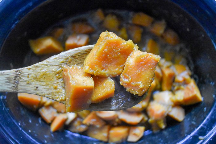 scooping candied sweet potatoes out of slow cooker crock