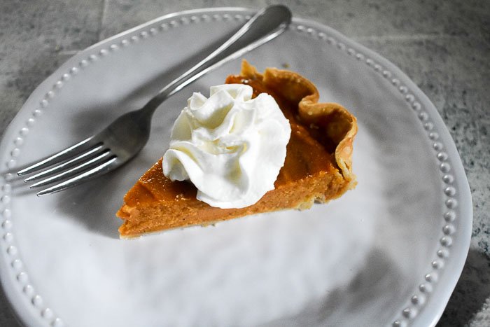 slice of sweet potato pie topped with whipped cream.
