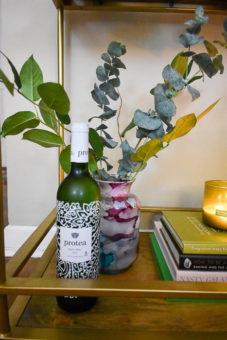 bottle of wine and greenery arrangement in watercolor vase
