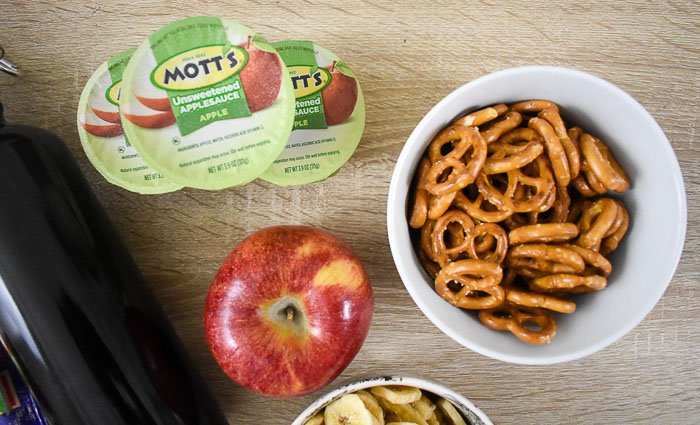 mott's unsweetened applesauce, an apple, and a bowl of pretzels