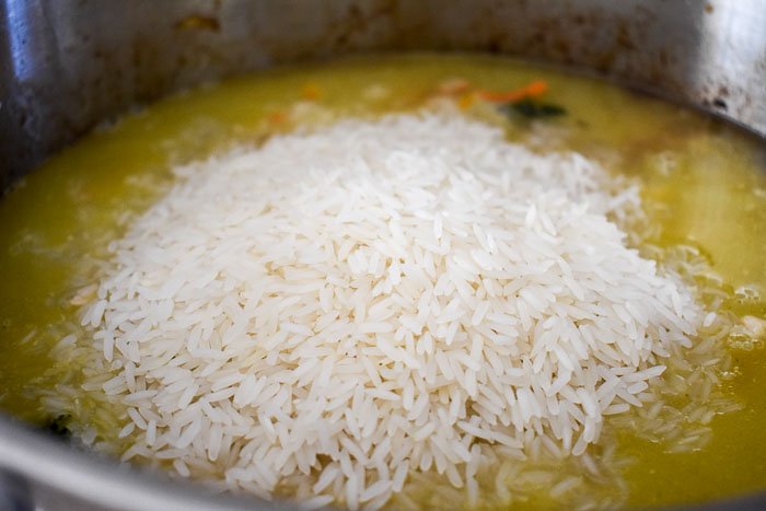 rice in a pot of broth, chicken, and vegetables