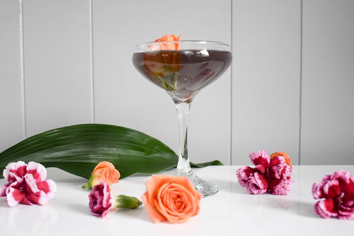 purple gin cocktail surrounded by edible flowers