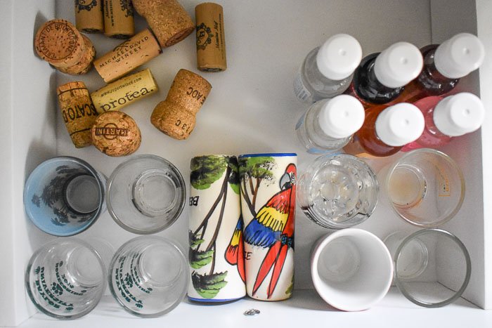 assortment of shot glasses, wine corks, and mini liquor bottles inside a drawer
