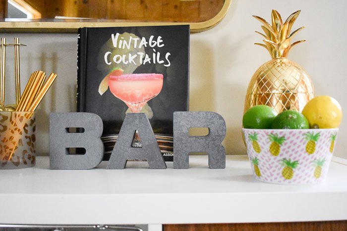 Vintage Cocktails book and other accessories on top of a home bar cabinet