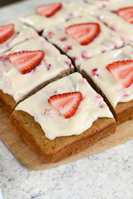 sliced strawberry cream cheese sheet cake decorated with fresh strawberry slices.