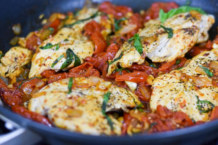 chicken breasts and sauteed tomatoes with basil in pan
