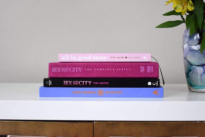 stack of coffee table books from tory burch, sex and the city, and kate spade