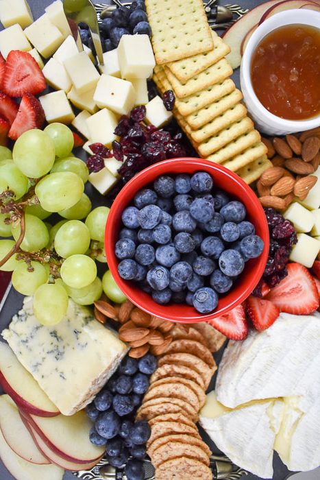 cheese board with assorted fruit, honey, crackers, and cheese