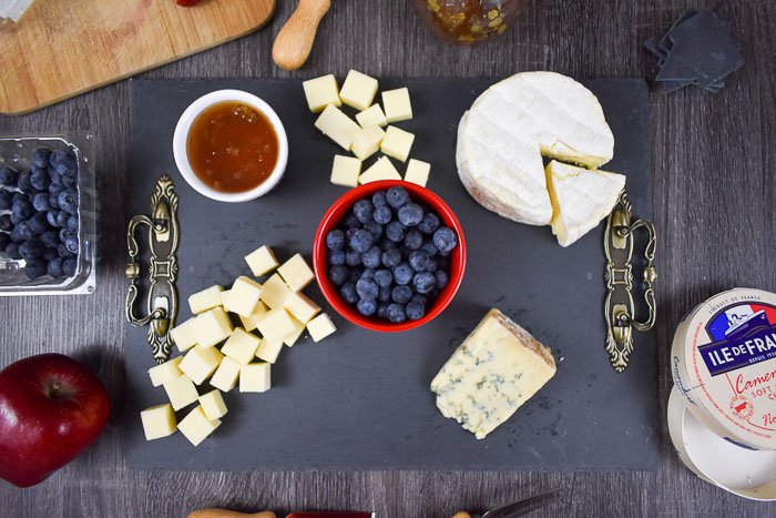 white cheddar, honey, blueberries, camembert, and blue cheese on slate cheese board