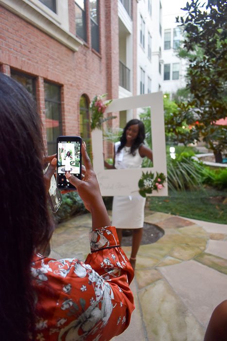 bride posing with photo booth frame at bridal shower