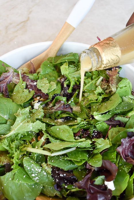 pouring champagne dressing over salad