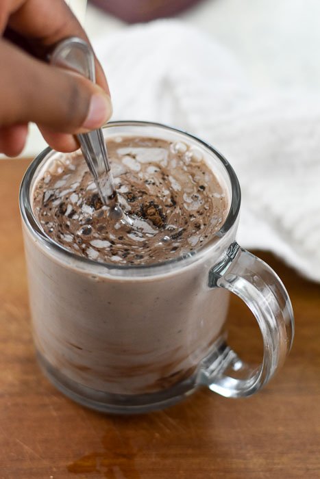 stirring mug of vegan hot cocoa