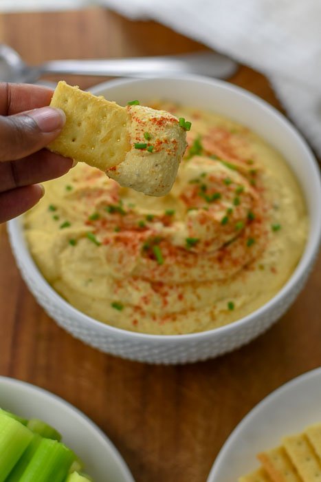 scooping deviled egg dip with cracker.