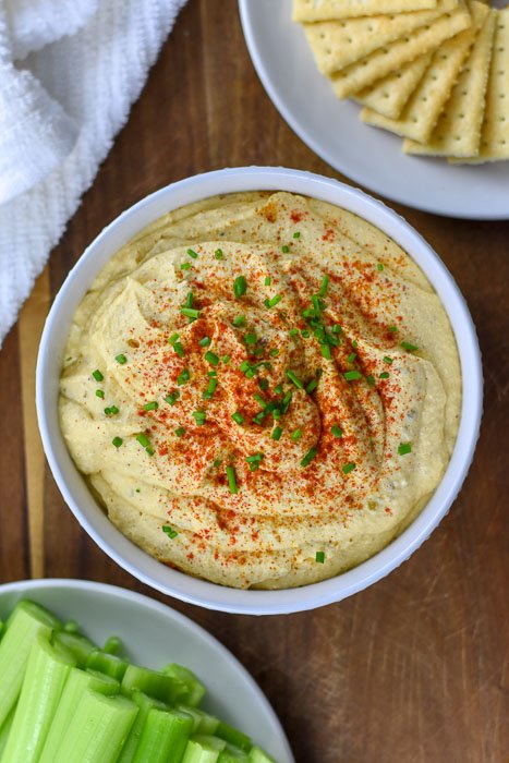 deviled egg dip topped with chopped chive blades and paprika.