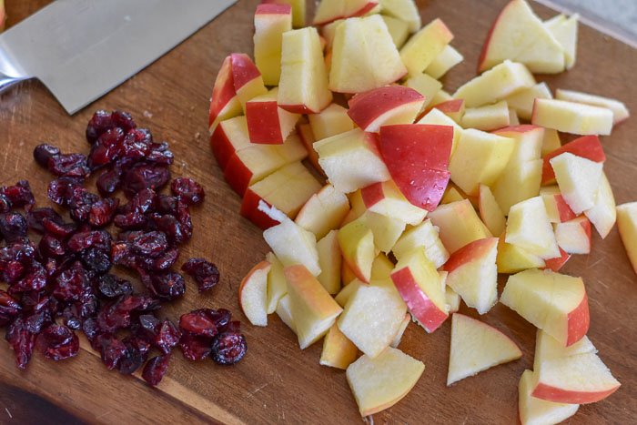 dried cranberries and chopped apple on cutting board