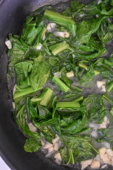 collard greens cooking with garlic and onion.