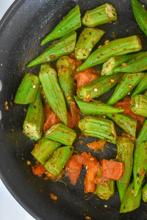 okra, tomato, and crushed red pepper in pan.