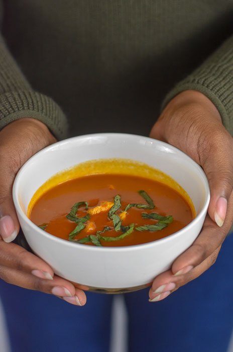 holding bowl of tomato basil chicken soup