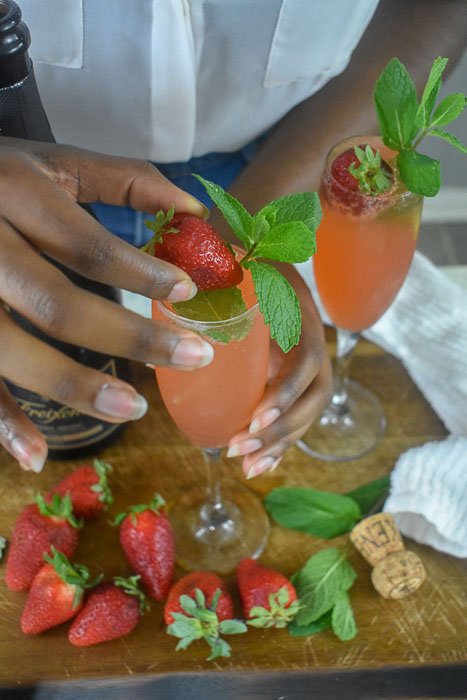 adding fresh strawberry to strawberry mint mimosa.