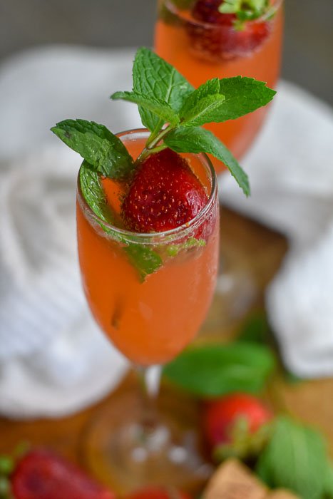 two strawberry mint mimosas with fresh strawberries and mint.
