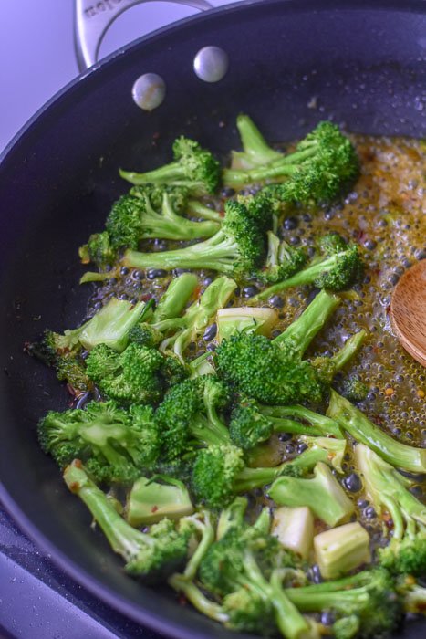 cooking broccoli florets in citrus sauce.