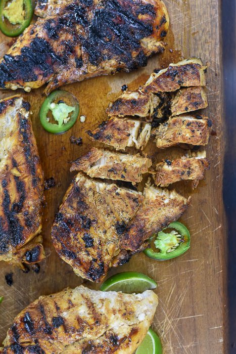 sliced jalapeño lime chicken breast on wooden cutting board.