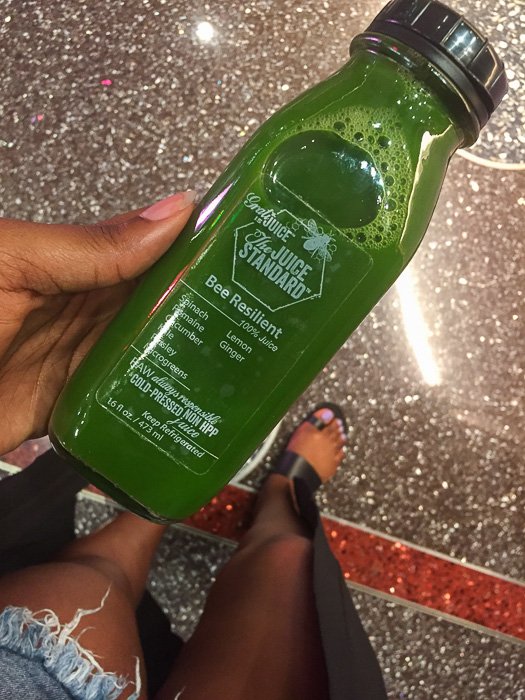 holding green juice from The Juice Standard.