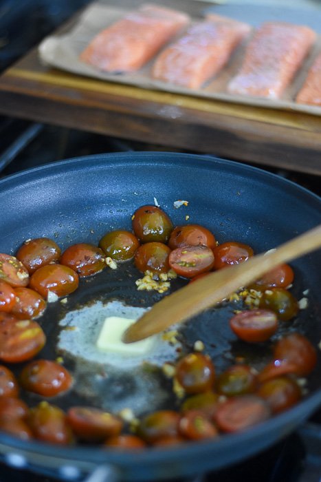 melting butter into skillet with baby tomatoes and minced garlic