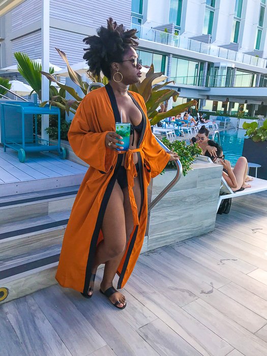 Dash of Jazz wearing orange kimono coverup at Serafina Beach Hotel pool