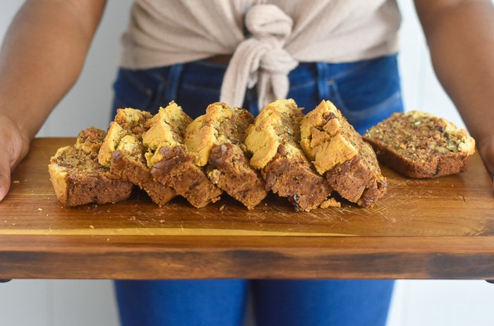 holding slices of baked banana bread laid on wooden cutting board.
