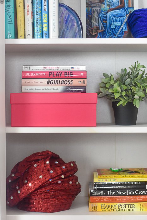 Nigerian gele, books, and succulent plant styled on IKEA Hemnes bookshelf