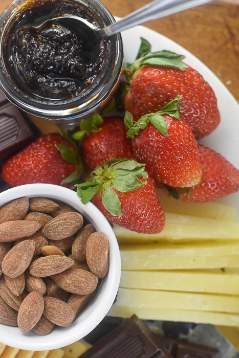strawberries, fig jam, and raw almonds on simple cheese board.