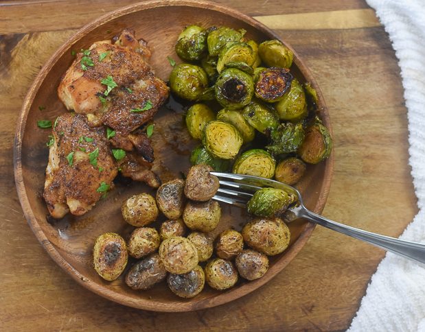 honey mustard chicken, baby potatoes, and spicy honey roasted brussels sprouts on wooden plate.
