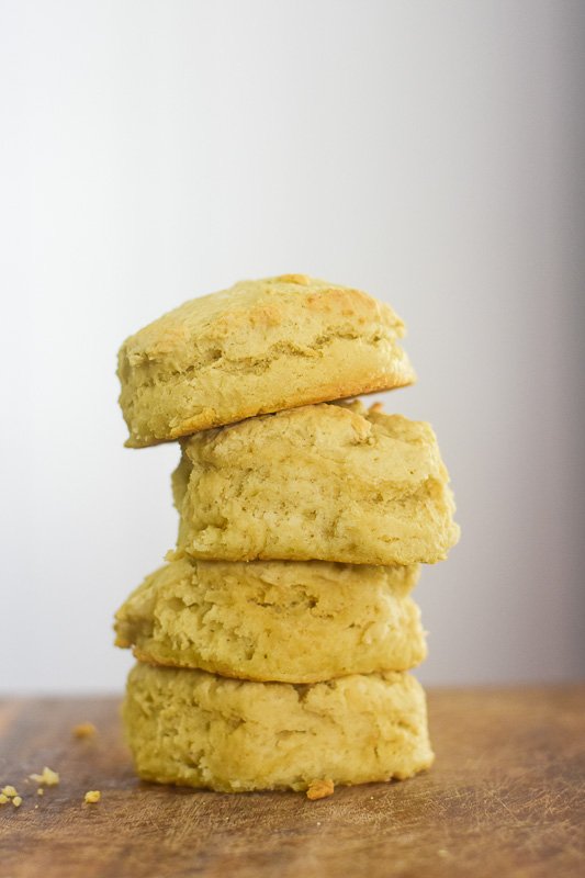 stack of four vegan buttermilk biscuits on wooden cutting board.