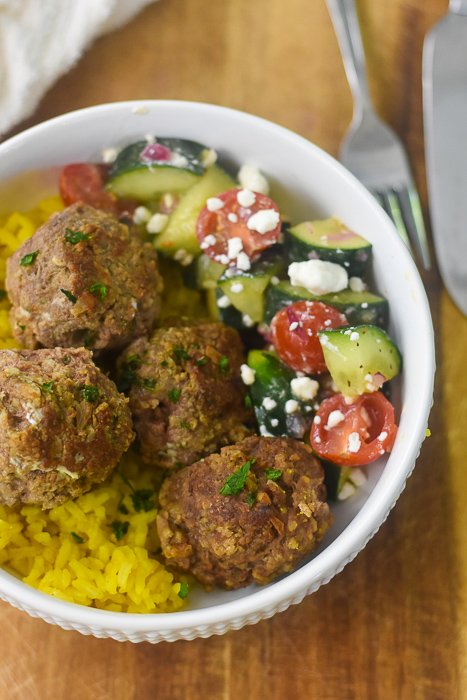 juicy lamb meatballs, Greek salad, and yellow rice in a power bowl