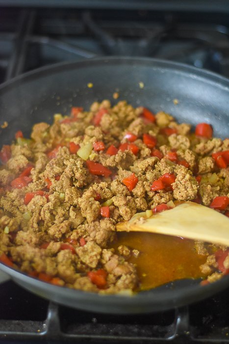 cooking taco filling with ground beef and red bell peppers.