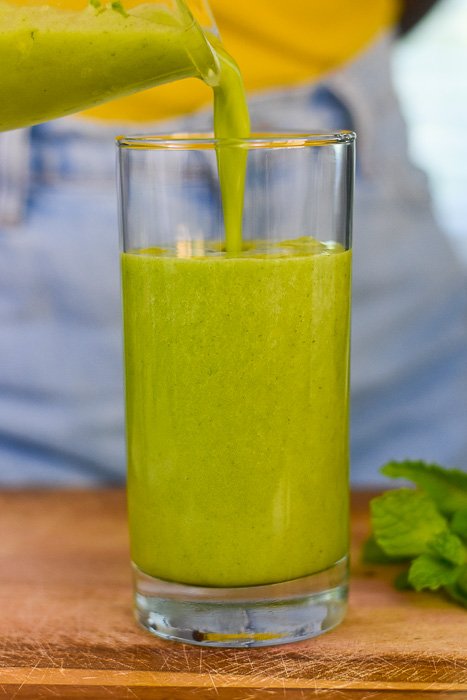 pouring green smoothie into glass