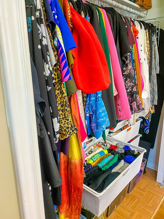 organized clothing closet with hung items and items folded in hanging drawers