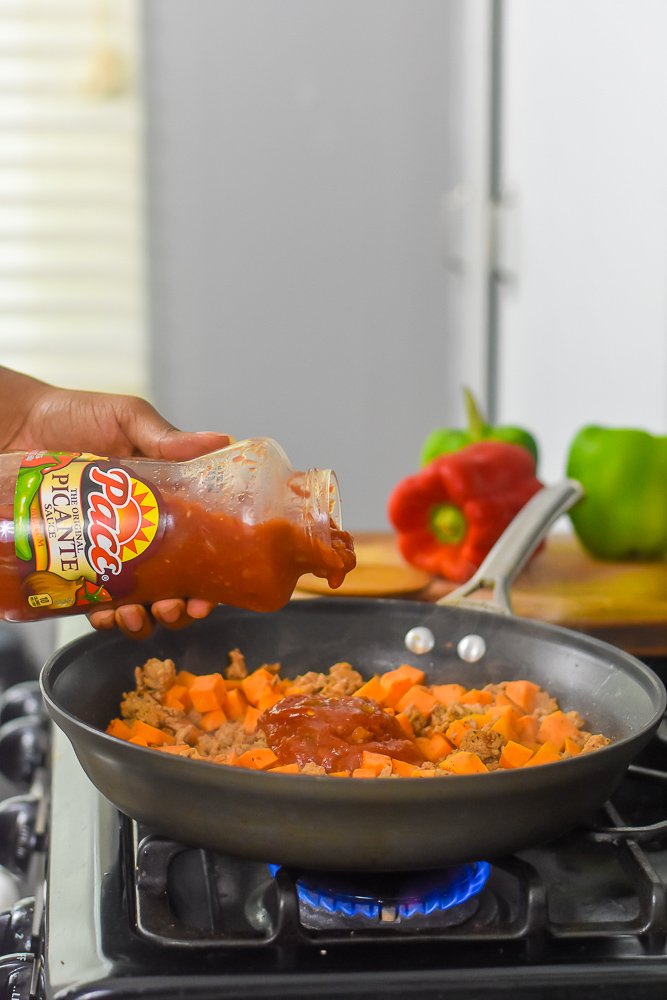 pouring Pace Picante Sauce into pan of Tex Mex stuffed pepper filling