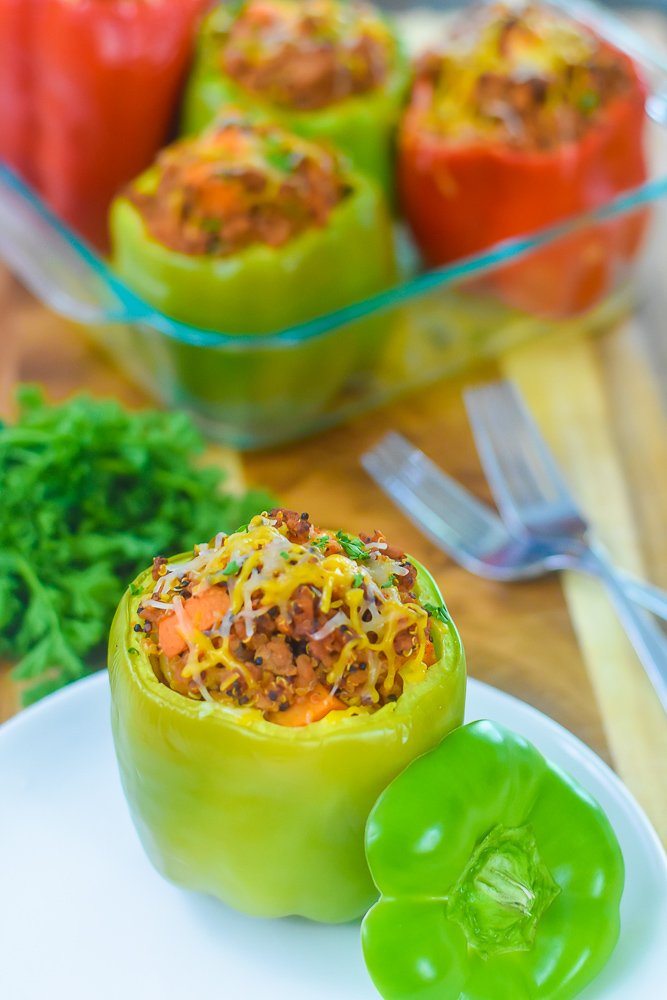 stuffed green bell pepper on a plate with more stuffed peppers in background