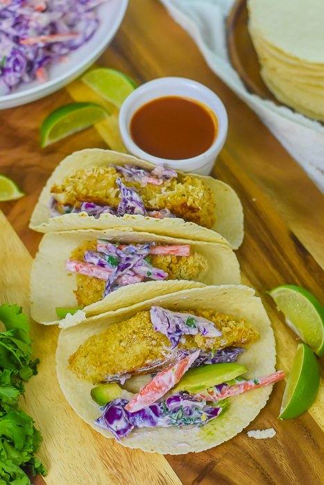 three fish tacos and garnishes on cutting board