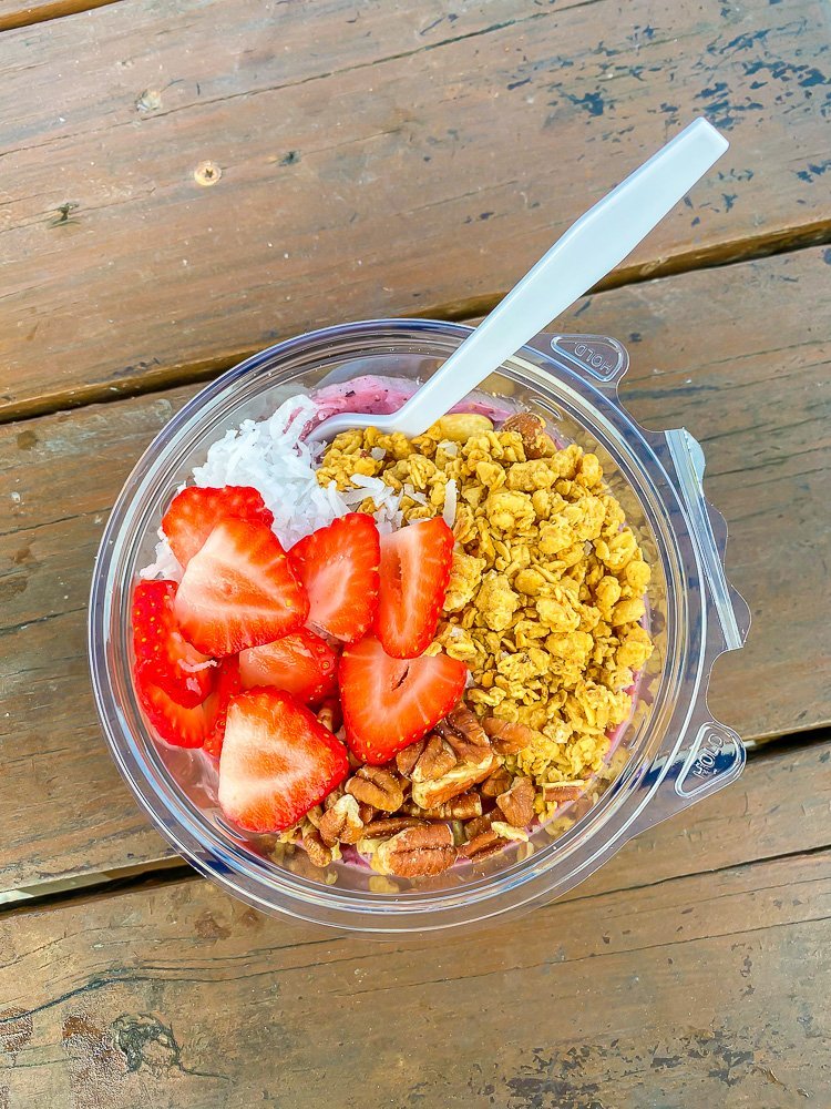 acai bowl with granola, pecans, and sliced strawberries