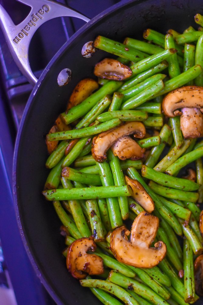pan of cut green beans and mushrooms cooked in salt, papper, and garlic cooked in calphalon skillet.